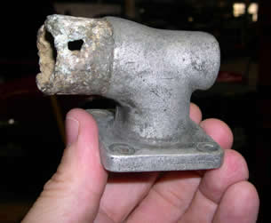 Original water pump manifold for 1922 Bugatti with damage from corrosion visible around the tube that accepts a flexible rubber water hose.